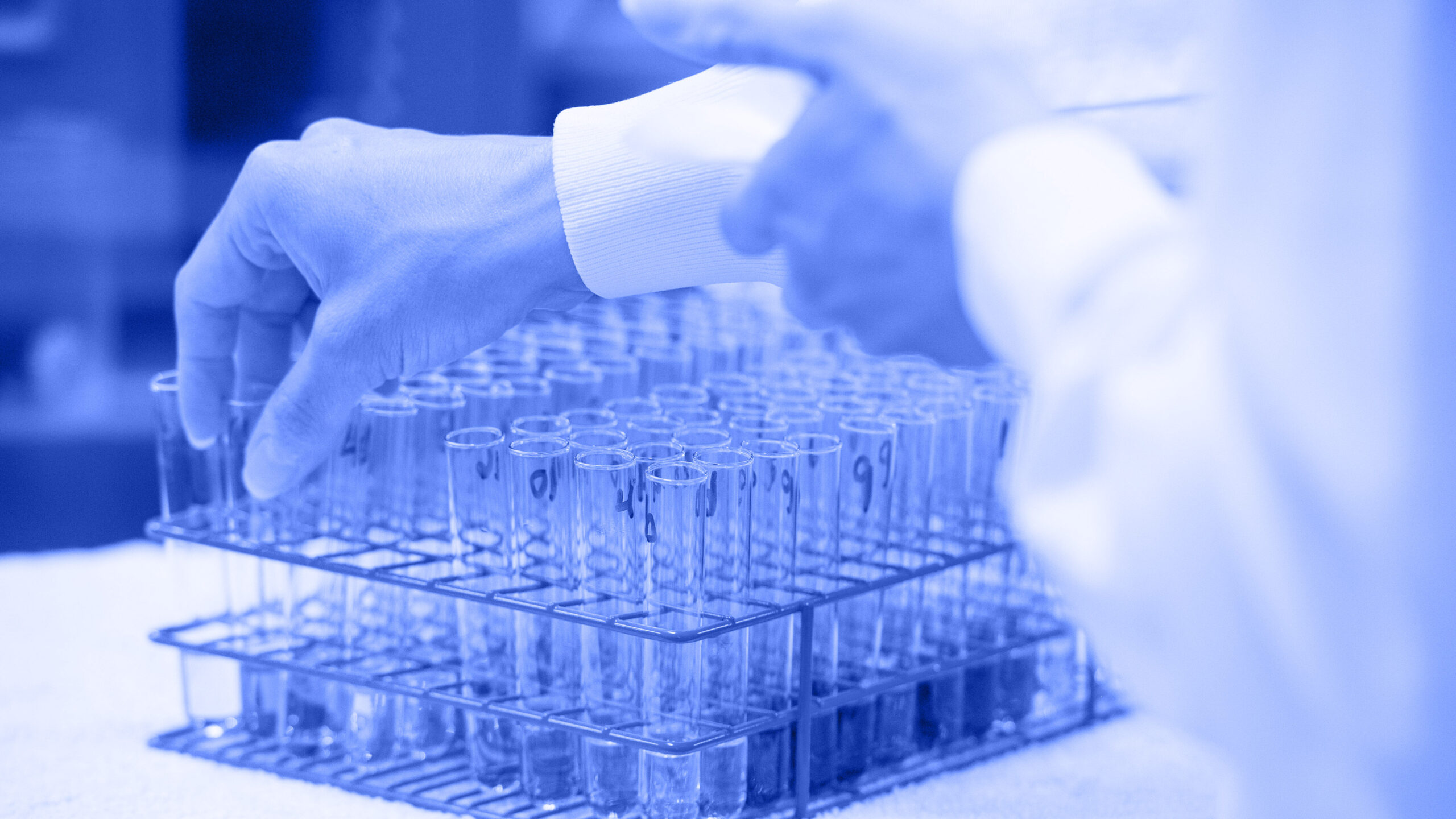 An analyst reaches for a test tube from a batch of test tubes.